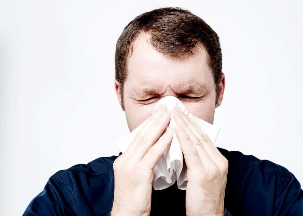 man sneezing into tissue