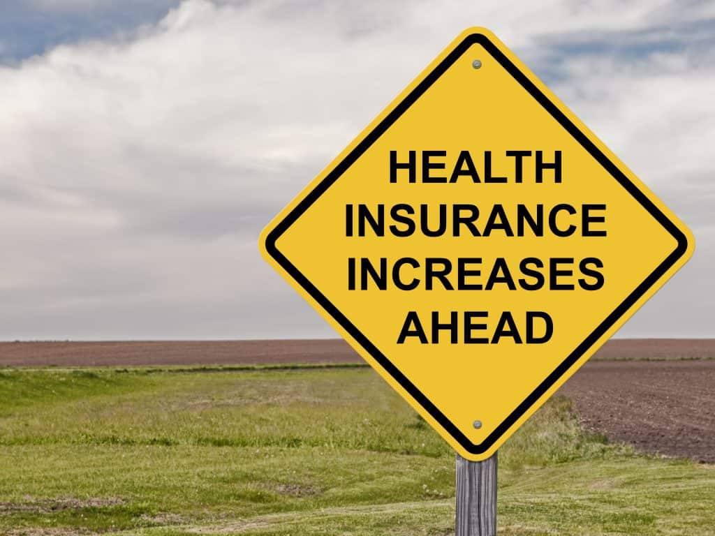 yellow road sign showing health insurance increases ahead