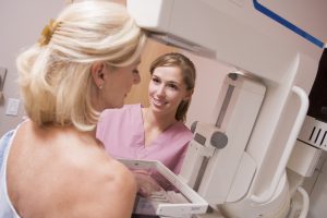 nurse performing a mammogram on a woman