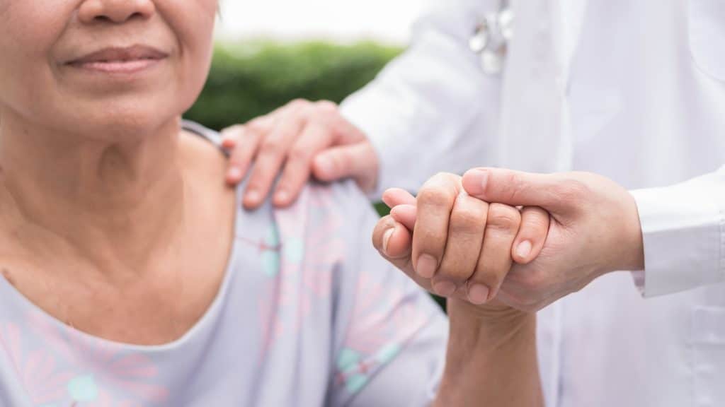 doctor holding hand of senior woman